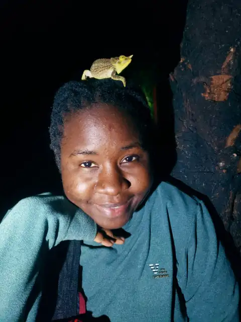 Perpetua Nyagwaswa, Operations Manager at Ecolegacy Africa, with a chameleon on her head